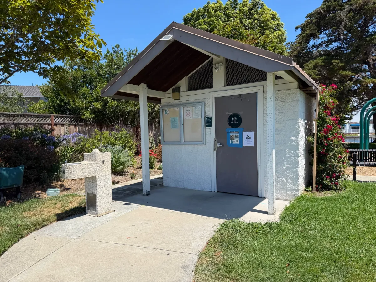 Bathroom and water fountain located next to swings