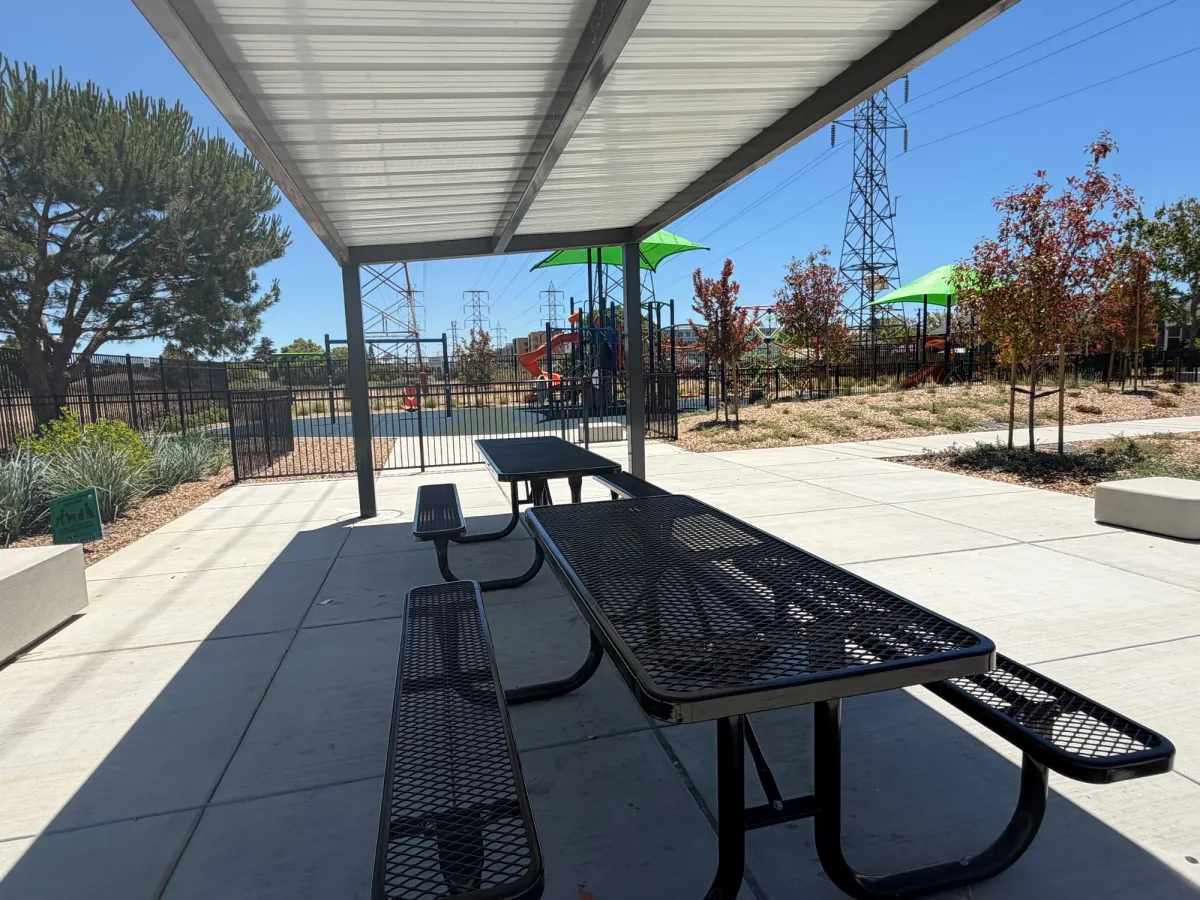 Shaded picnic tables provide direct oversight of the playground