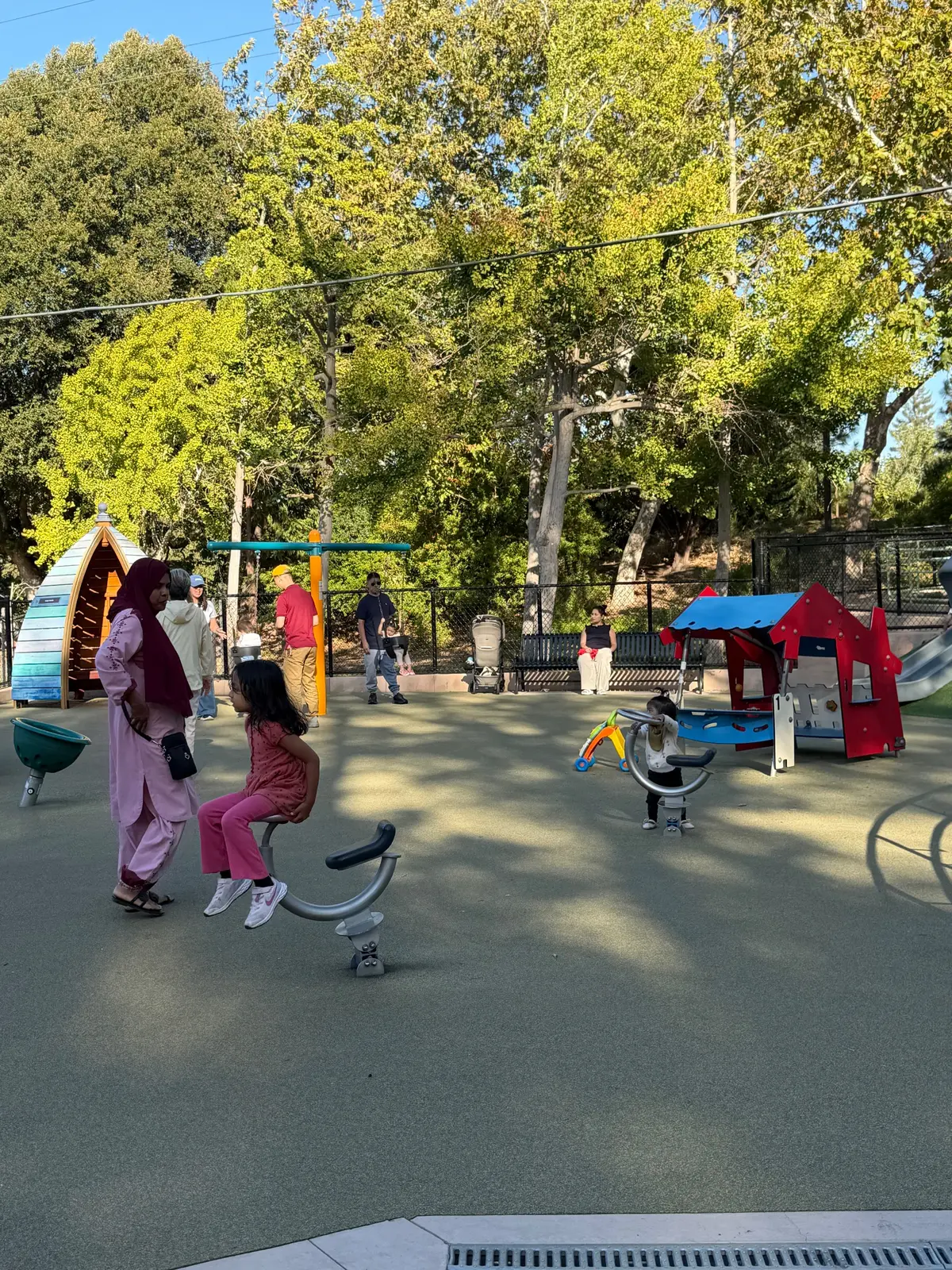 Toddler area with playhouse, ride on toys, spinners, and baby swings