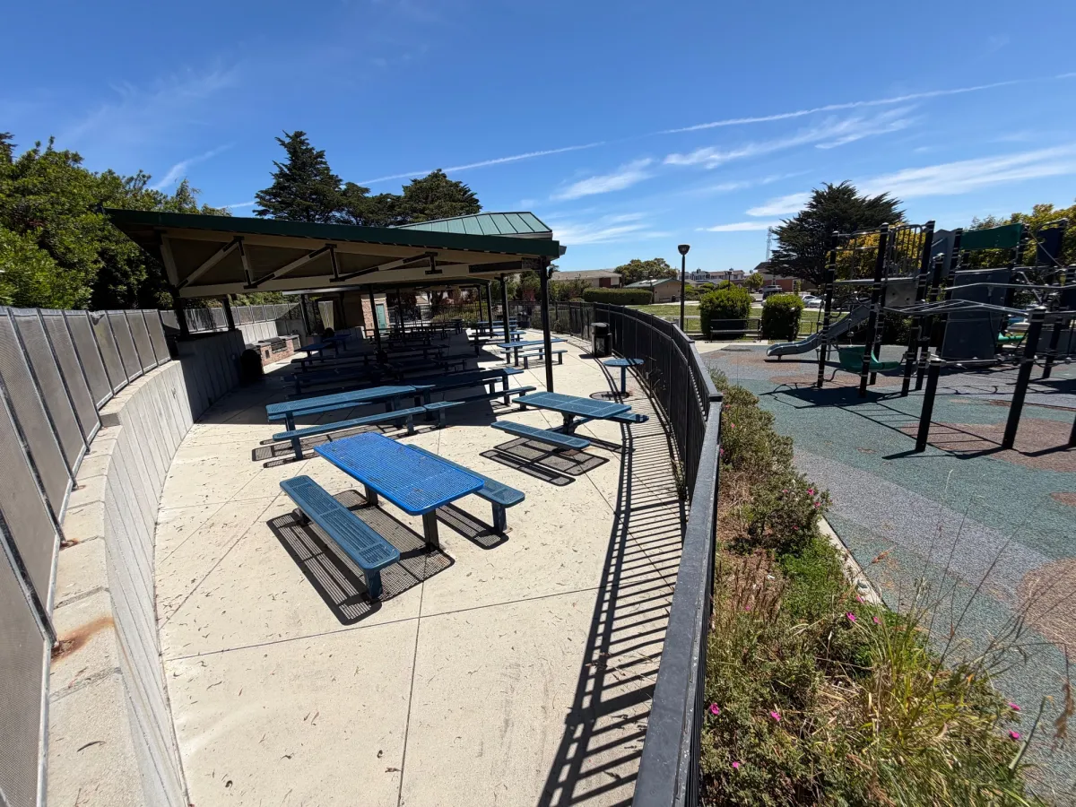Large cluster of shaded picnic tables next to big kid playground