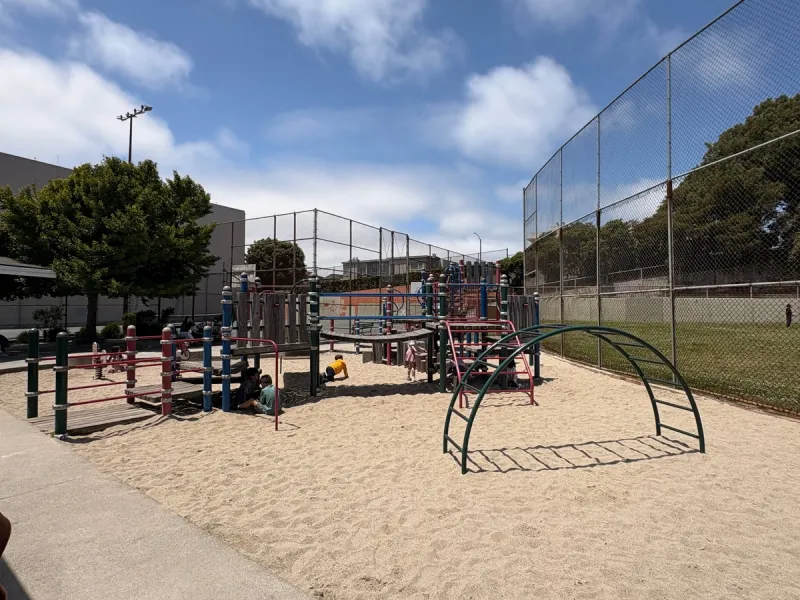 Main playground tucked into the corner of a baseball field