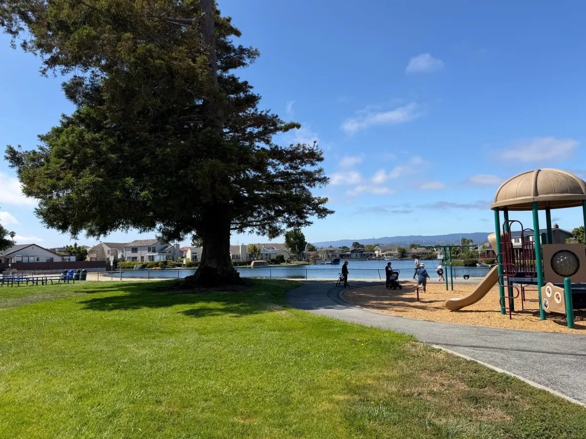Picnic tables are in between the two playgrounds, on the grassy field