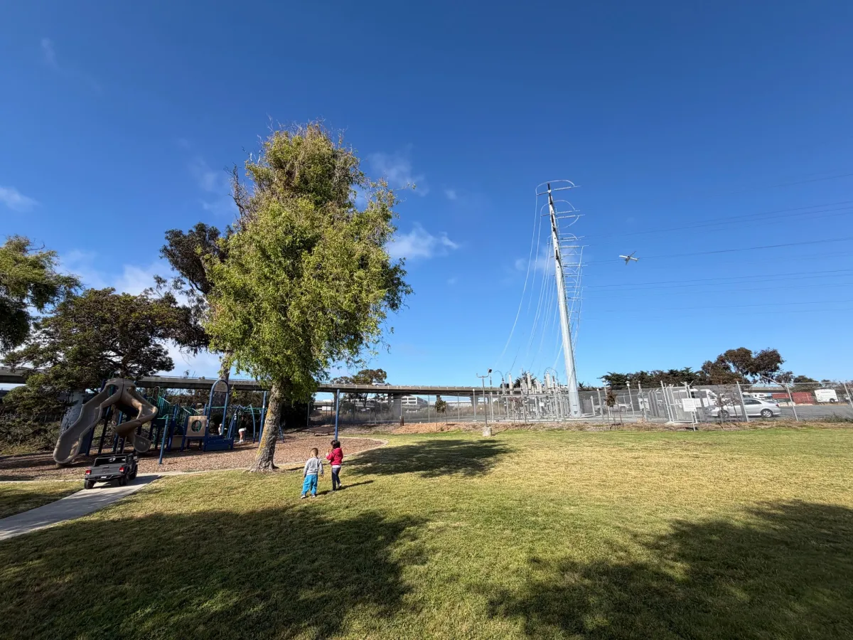 Giant power lines to the side of the playground, directly in the flight path of planes overhead