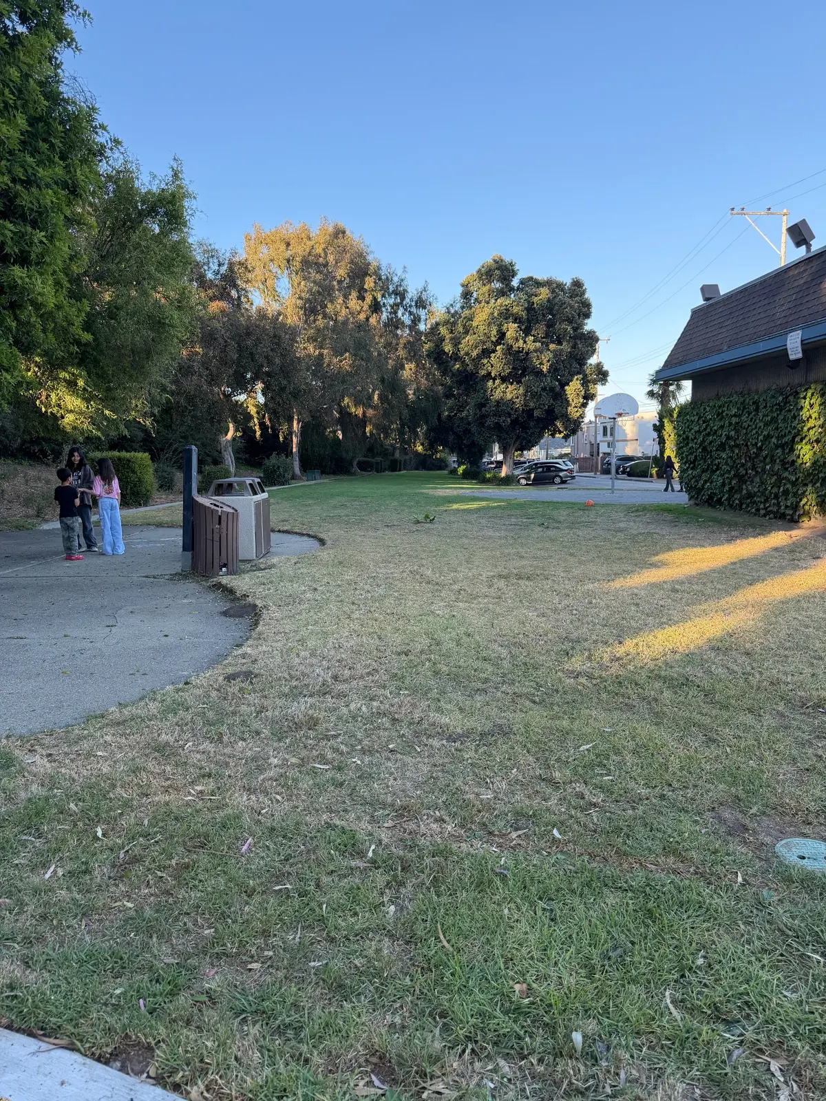 Grass field on other side of playground with basketball court in back