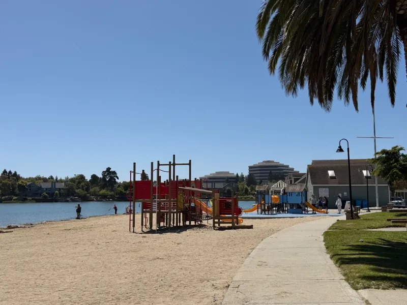2 playgrounds on the sand directly in front of the lagoon and the bathroom next door