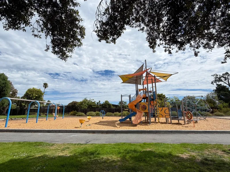 Large shade coverings, swings to the left, spinners, multiple slides, and climbing structure in back