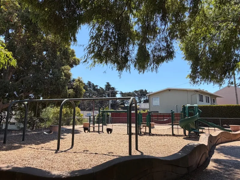 Toddler and big kid swings in front of medium slides 
