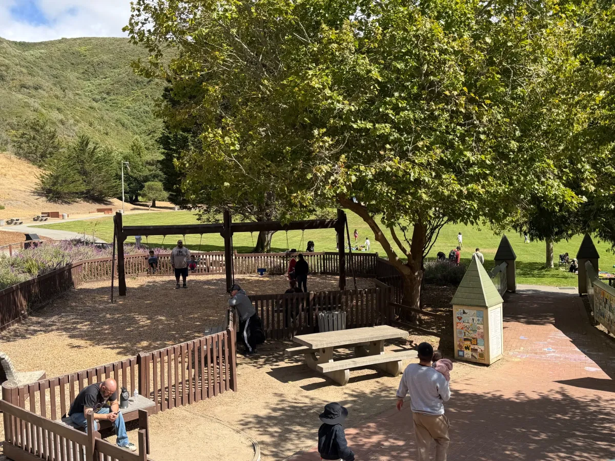 Picnic table at entrance to playground, grassy field in front