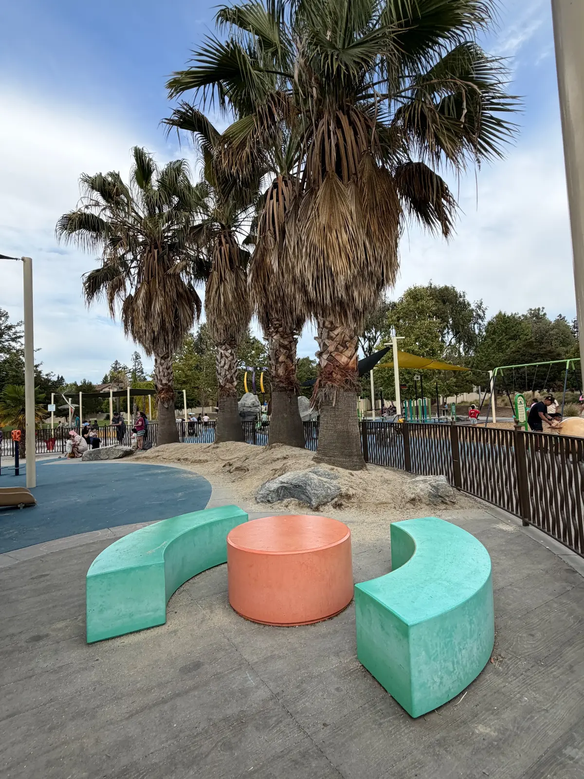 Playground bench seating with palm trees in back
