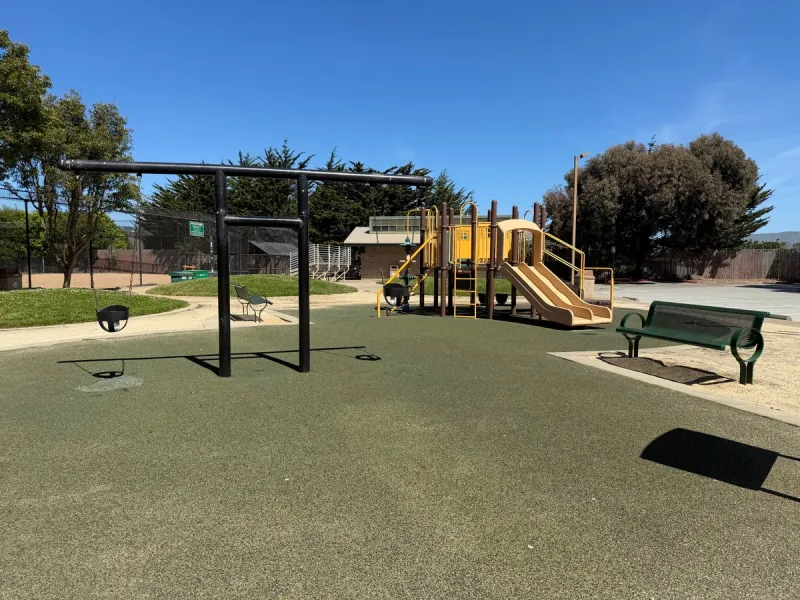 Unassuming little playground with toddler swings and small playstructure