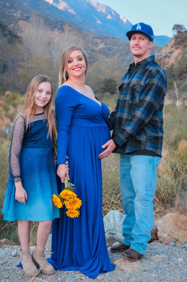 Family of three with sunflowers and the mountains in the distance
