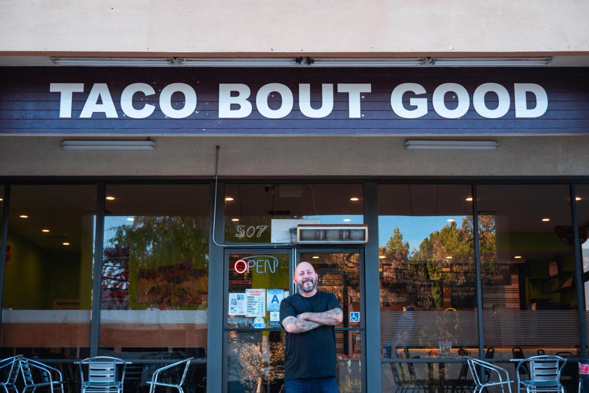 Owner standing with arms crossed in front of the Taco Bout Good storefront
