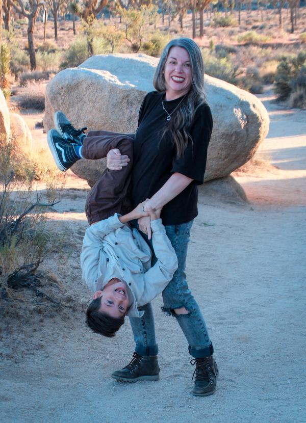 Mom laughing as her son hangs upside down in her arms