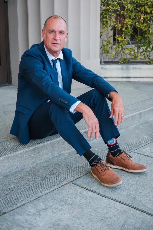 Candidate seated casually on stone steps in a blue suit