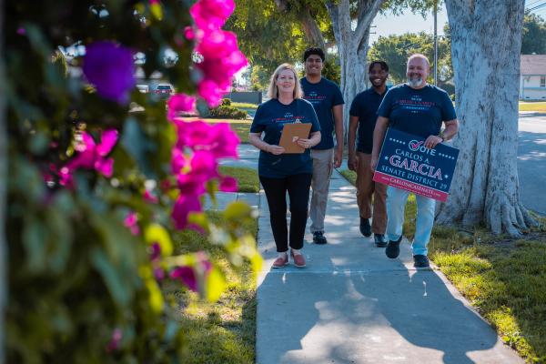 Campaign volunteers walking a neighborhood street with signs and clipboards