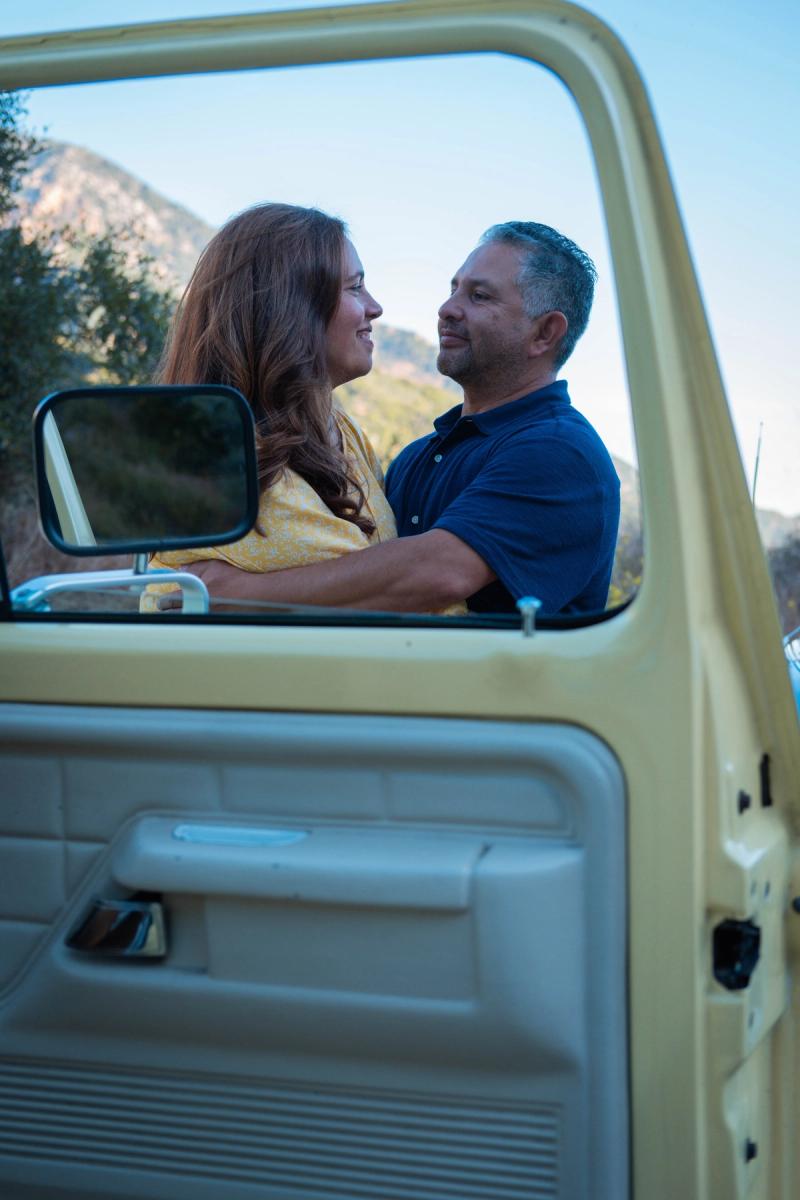 Couple leaning together in the open door of a cream pickup