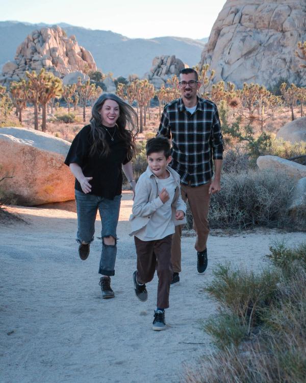 Family running toward the camera on a sandy desert trail