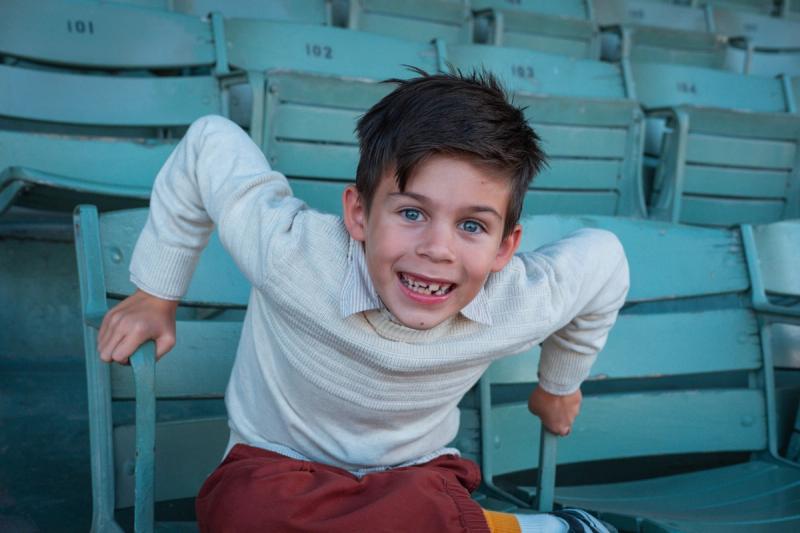 Boy making a goofy face while lounging in the grandstand seats