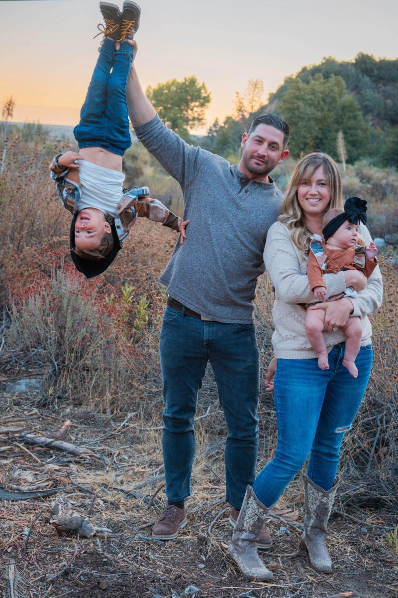 Dad flipping his giggling son upside down in a grassy field