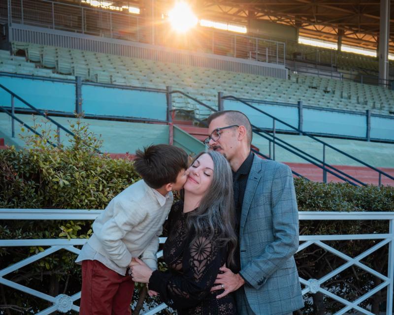 Family sharing a kiss at the Santa Anita racetrack railing at sunset