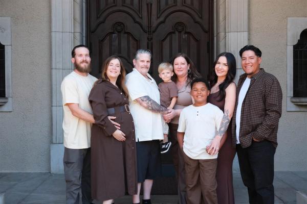 The whole family gathered in front of tall wooden doors and stone columns