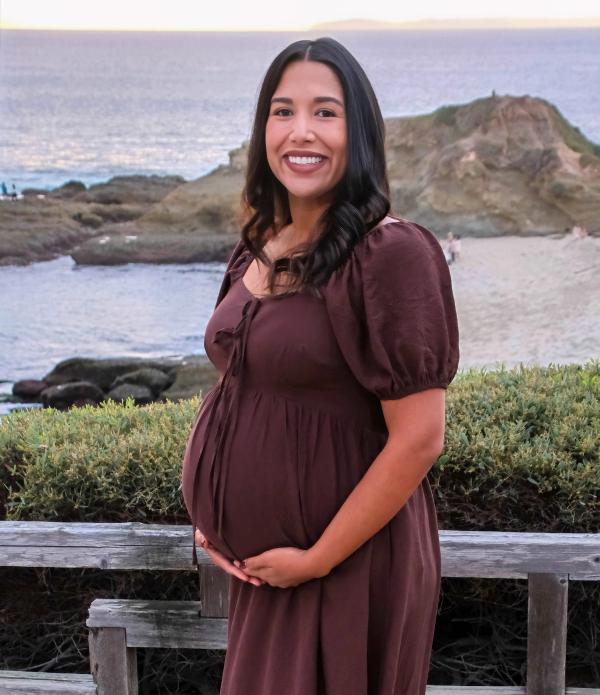 Expecting mom in a brown dress above a rocky coastline