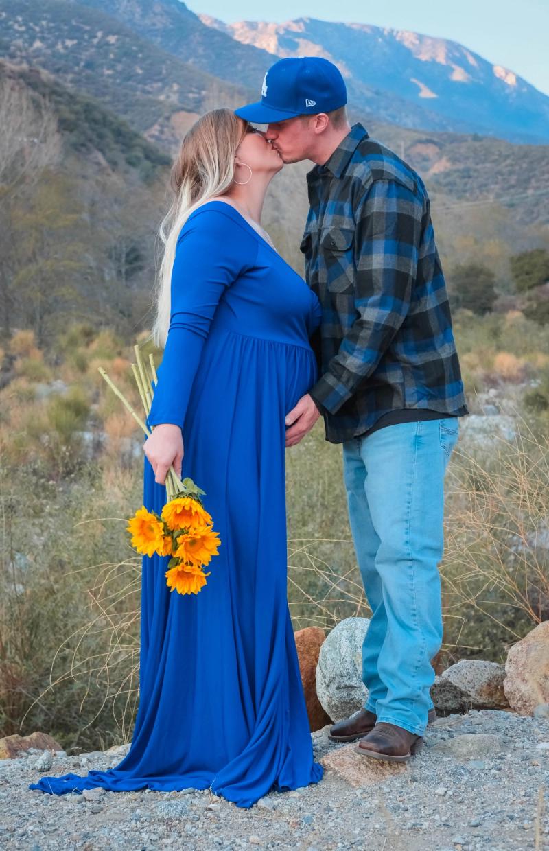 Couple kissing as she holds a bunch of sunflowers