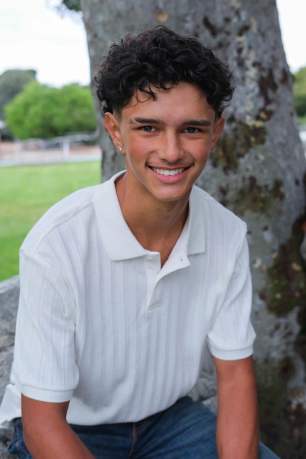 Close portrait of a smiling teen with curly hair in a white polo