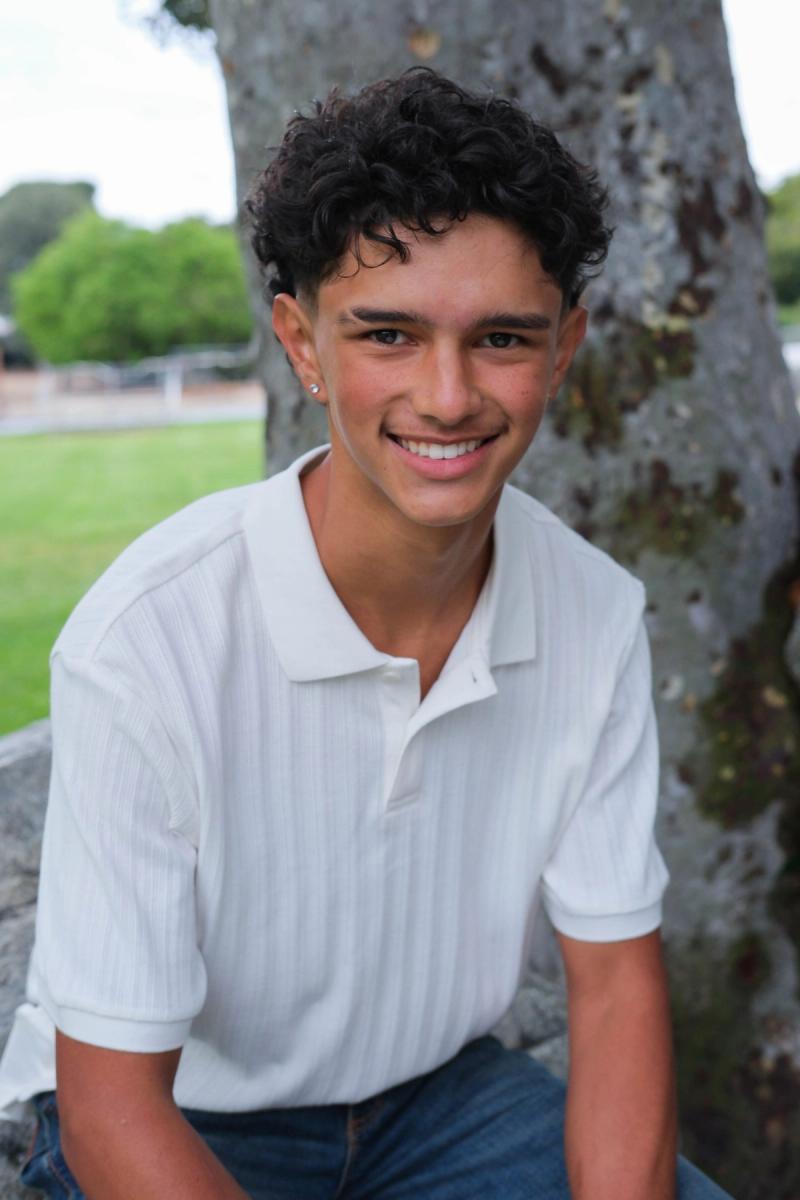 Close portrait of a smiling teen with curly hair in a white polo