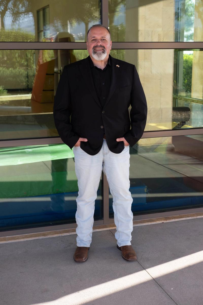 Candidate standing in front of glass doors with hands in pockets