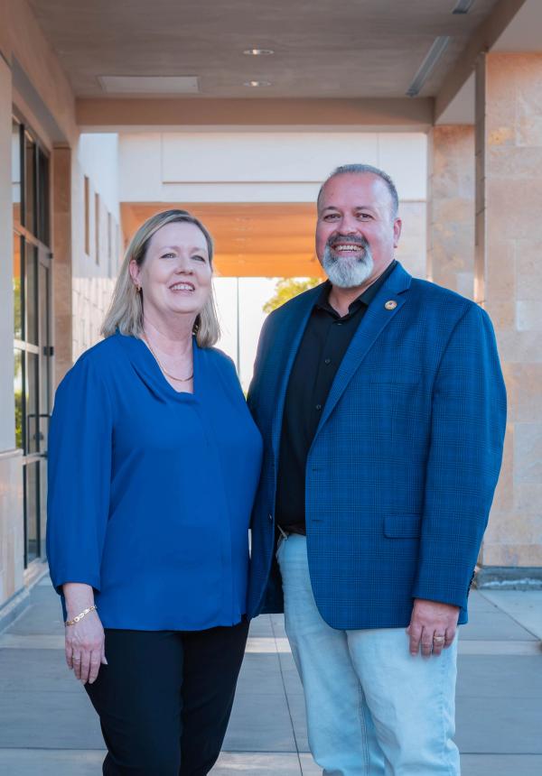 Candidate standing with his wife under a sunlit building arcade
