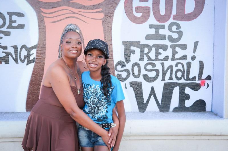 Mother and daughter smiling cheek to cheek against a painted wall