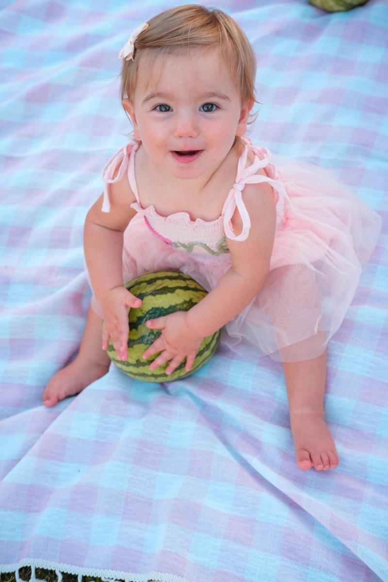 One-year-old grinning with both hands on a watermelon