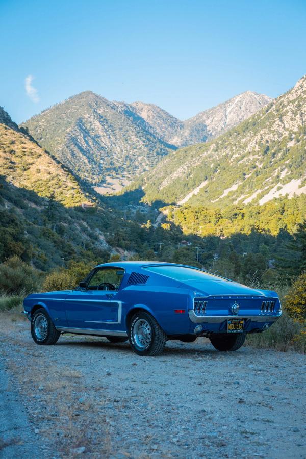 Blue Mustang fastback below rugged mountain peaks
