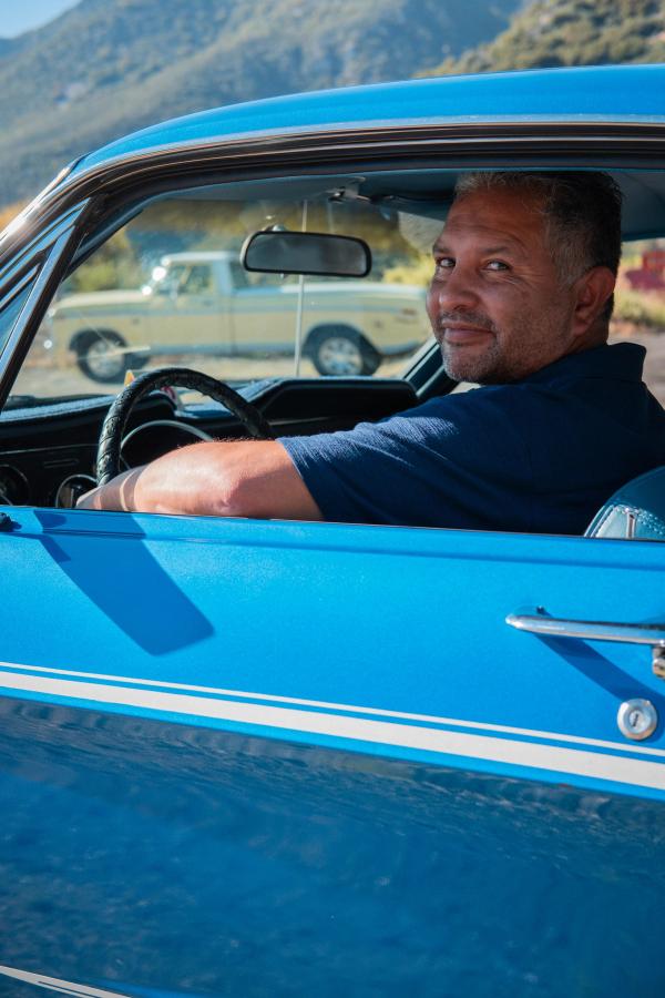 Man leaning out the window of his blue Mustang
