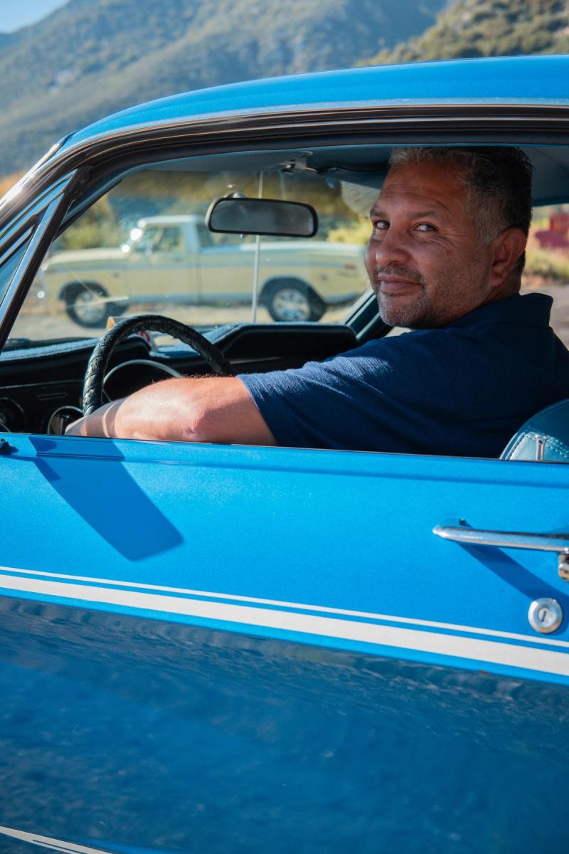 Man leaning out the window of his blue Mustang