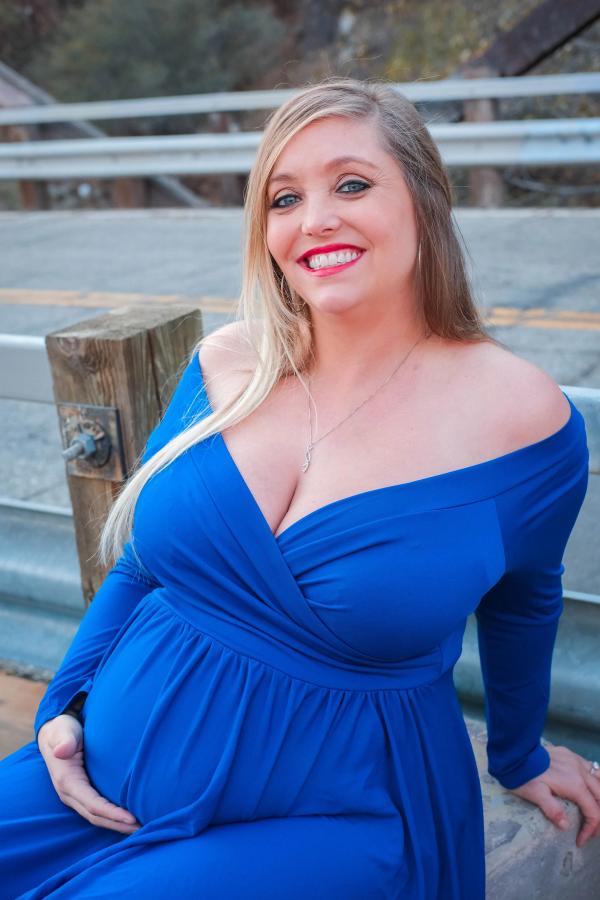 Close portrait of a laughing expectant mother in royal blue