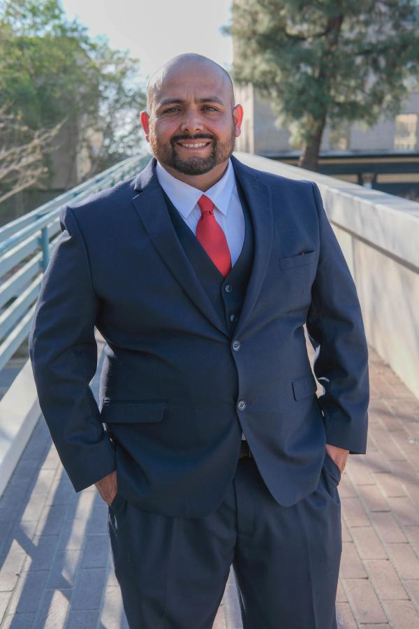 Candidate standing on a downtown walkway with hands in pockets