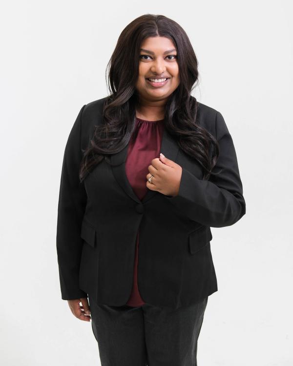 Standing portrait of a woman in a black suit and burgundy blouse