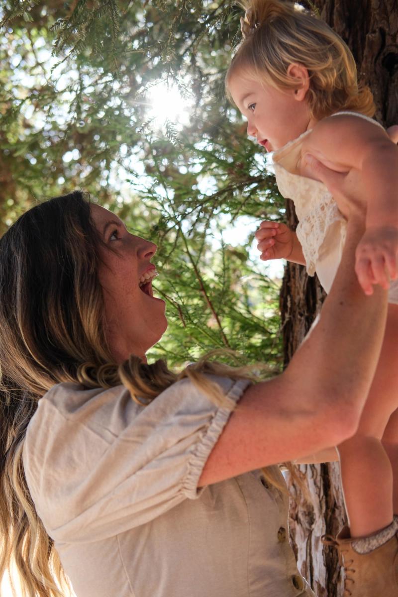 Mom lifting her daughter overhead as they smile at each other