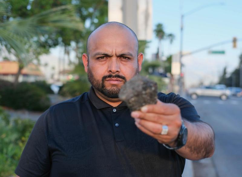 Candidate holding up a chunk of broken pavement on a city street