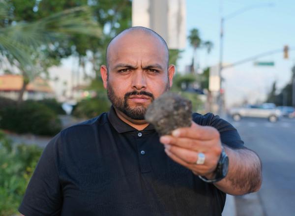 Candidate holding up a chunk of broken pavement on a city street