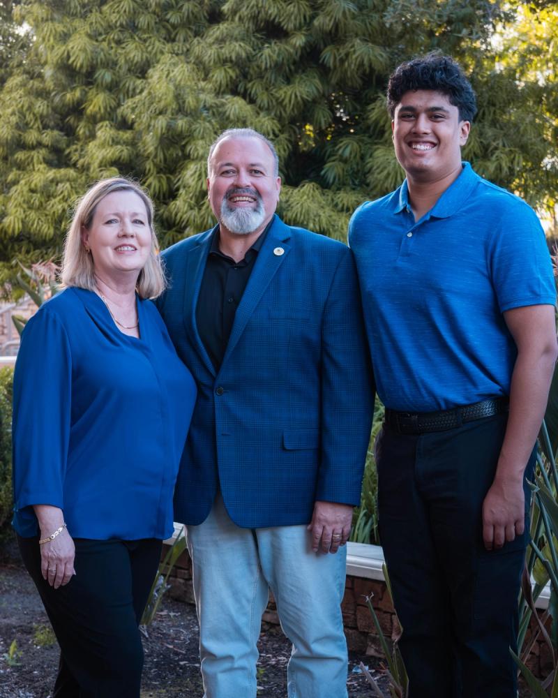 Candidate standing with his family in front of greenery