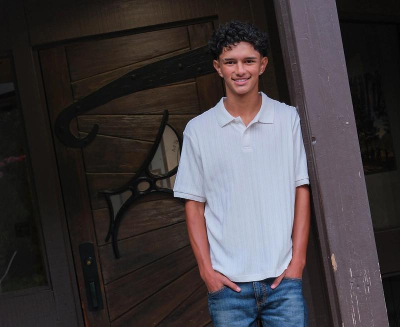 Smiling teen leaning in a carved wooden school doorway