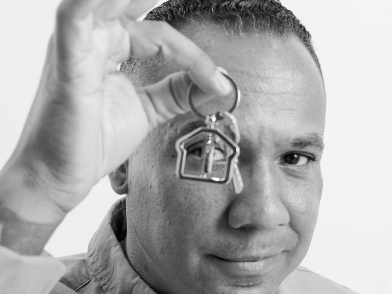 Black and white brand portrait of a real estate agent playfully holding up a house-shaped keychain