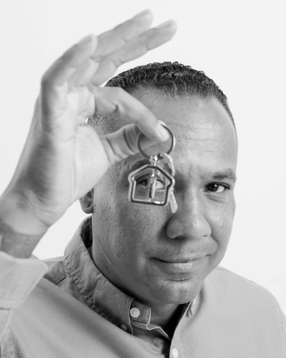 Black and white brand portrait of a real estate agent playfully holding up a house-shaped keychain