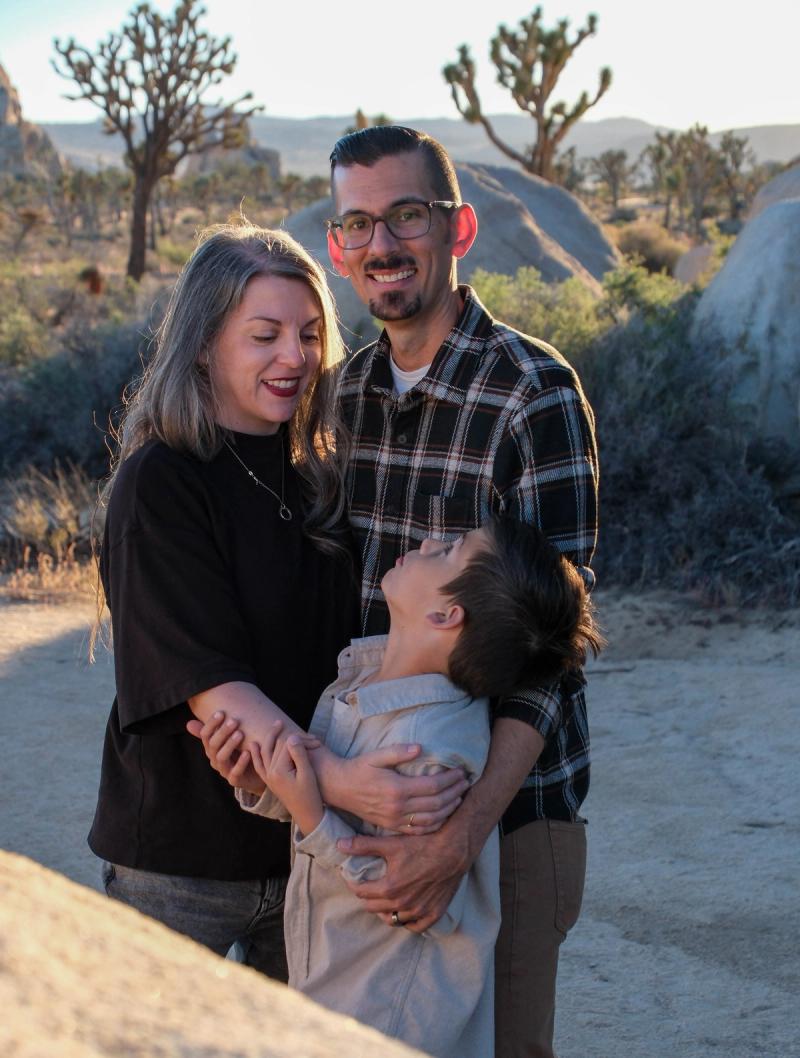 Parents hugging their son in warm golden-hour light in Joshua Tree