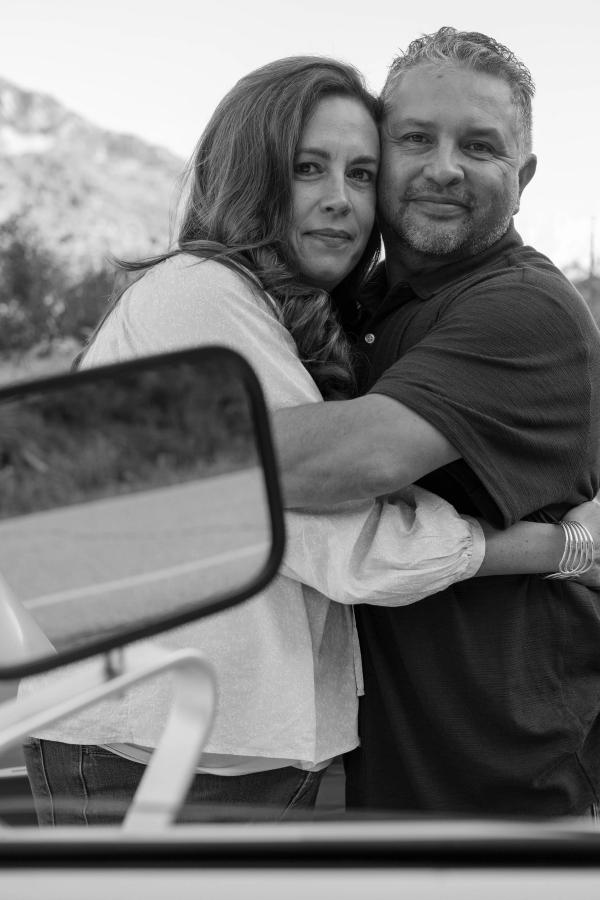 Black and white portrait of a couple embracing by the truck mirror