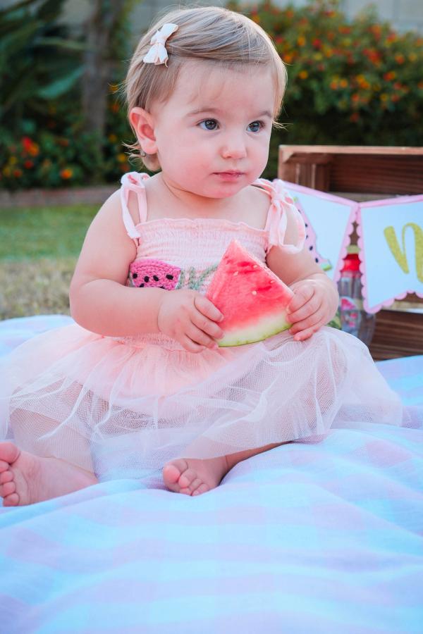 Little girl tasting a slice of watermelon for her first birthday