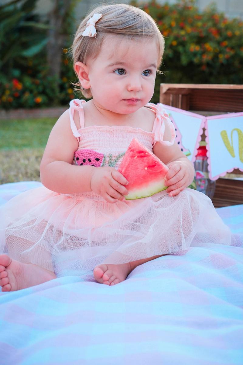 Little girl tasting a slice of watermelon for her first birthday